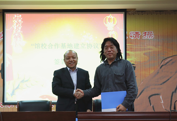 河南省美术馆副馆长于会见（右）与郑东新区教育文化体育局局长田国安（左）签署“馆校合作基地建立协议”