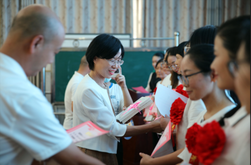 郑东新区龙子湖办事处主任李郑懿、郑州市第九十四中学校长张春旺为“优秀教师”颁发奖状